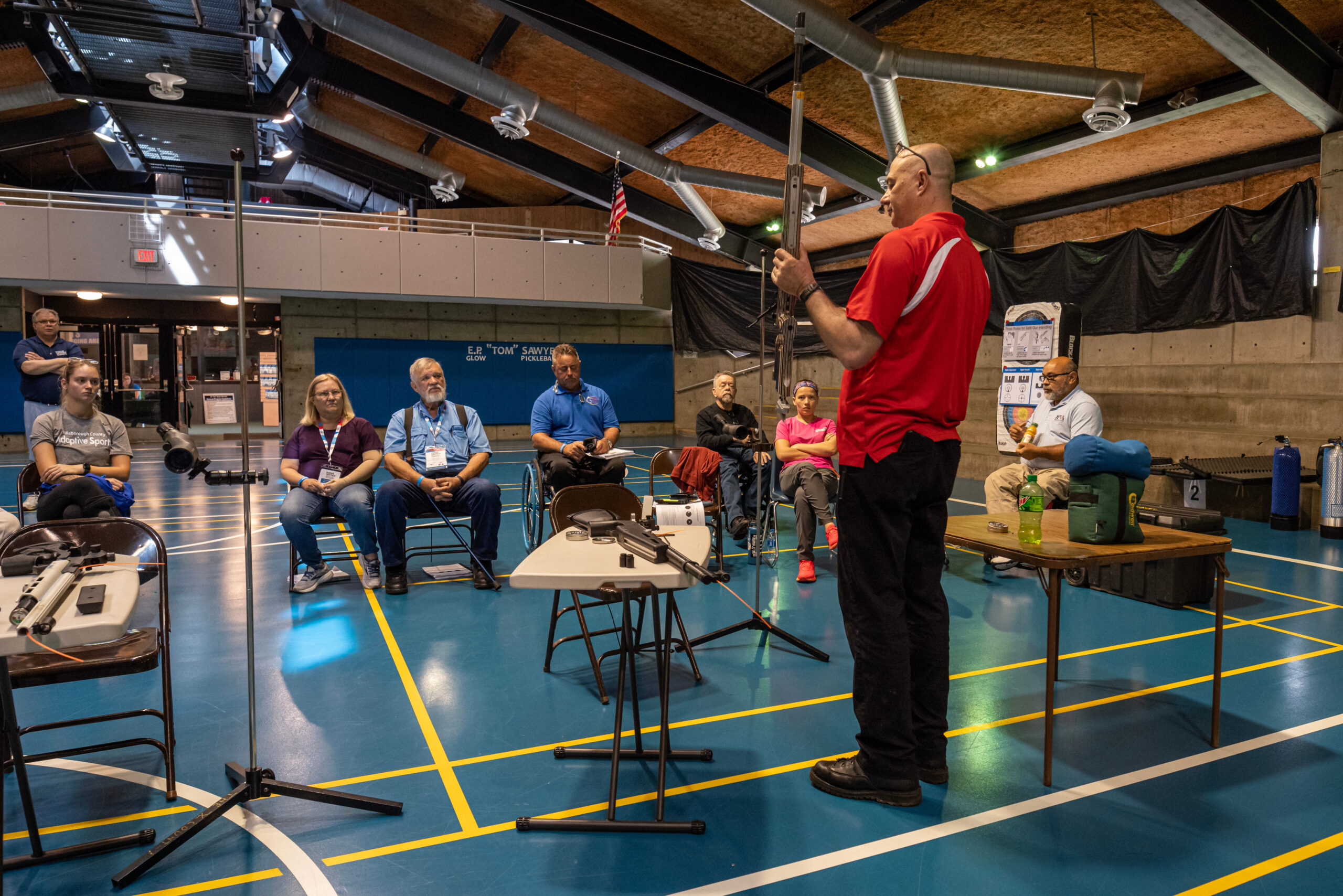Individual standing in front of room teaching participants about the sport of shooting