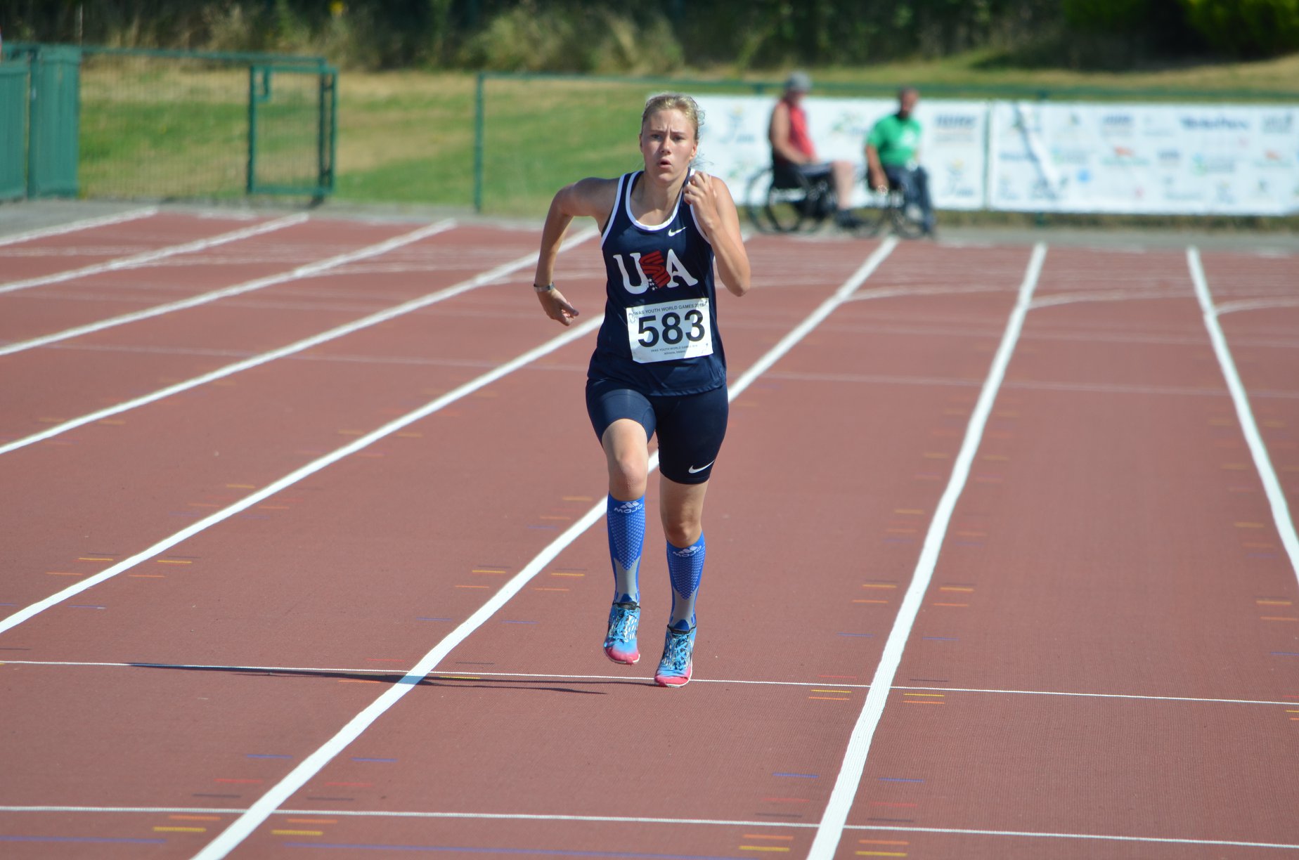 Person running on an outdoor track in a tank top and shorts that says USA