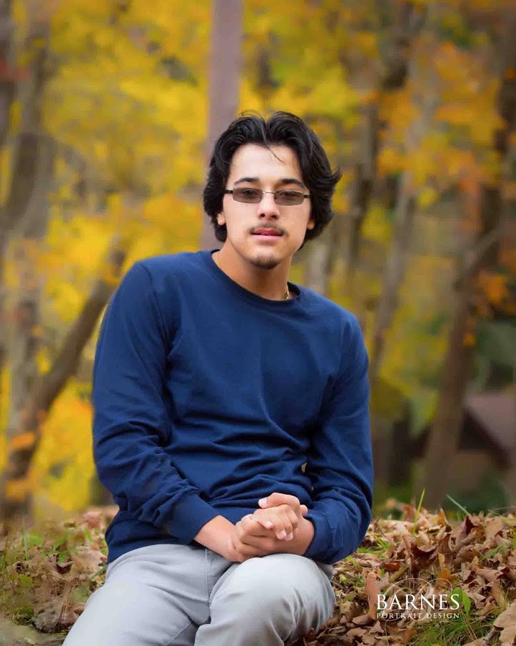 Male wearing a blue shirt and sunglasses smiling at the camera